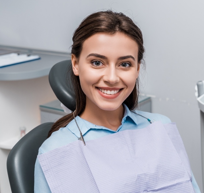 Smiling woman sitting in treatment chair at dental office in Eugene