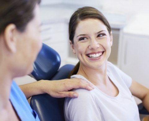 Woman in dental chair grinning at her dentist