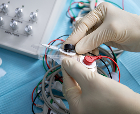 Gloved hands holding several electrodes and cords