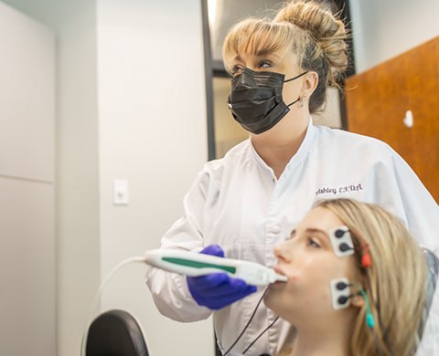 Dental team member taking scans of a patients teeth