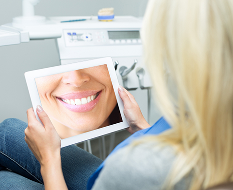 Dental patient holding a tablet showing a close up of a flawless smile