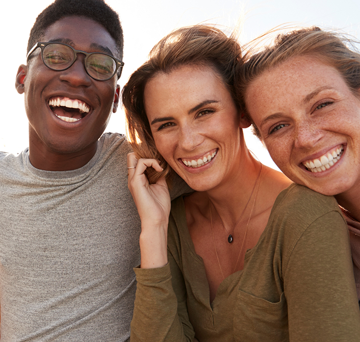 Three adults smiling with dental implants in Eugene