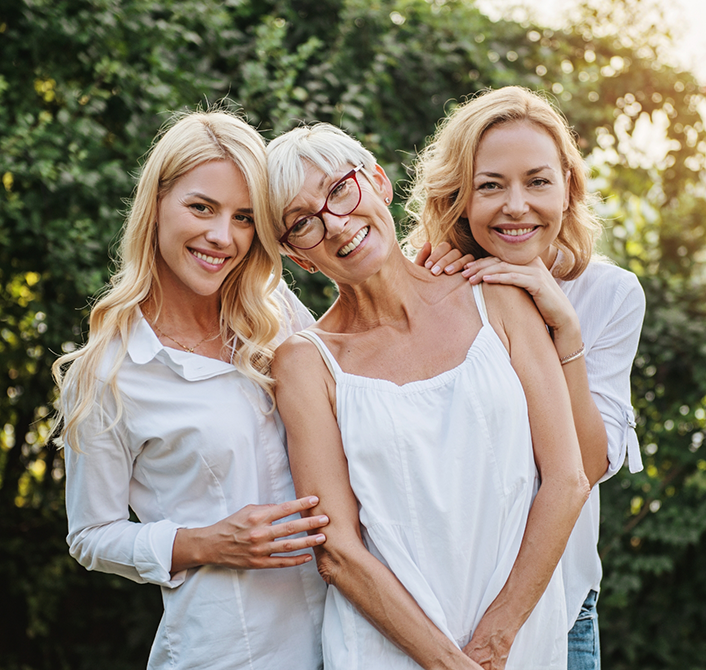 Three women outdoors smiling with same day dentures in Eugene