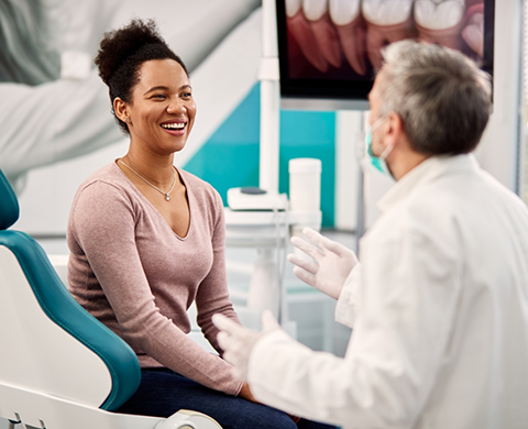 Woman in dental chair grinning at her dentist