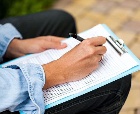 Person filling out a form on a clipboard