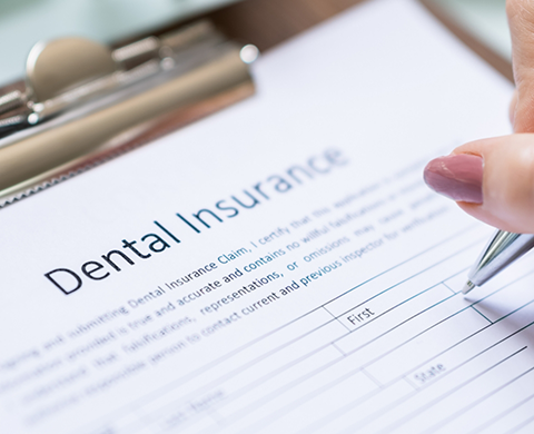 Person filling out paperwork for dental insurance in Eugene