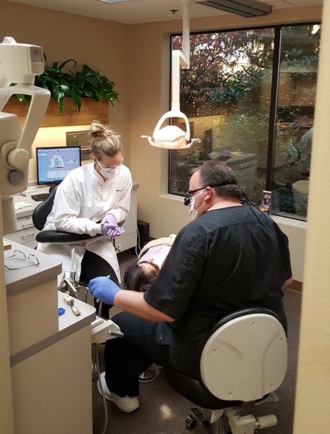 Doctor Sutter and dental assistant treating a patient