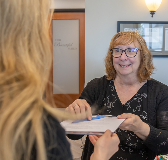 Dental team member handing a clipboard to a patient in Eugene dental office