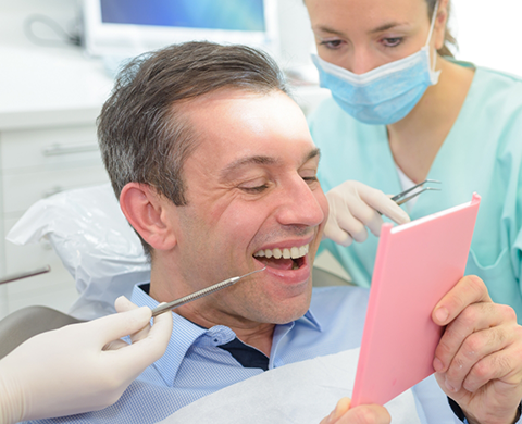 Dental patient looking at his smile in a mirror