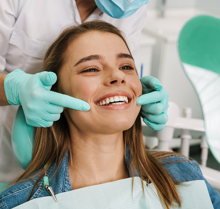 Young woman in dental chair grinning after restorative dentistry in Eugene