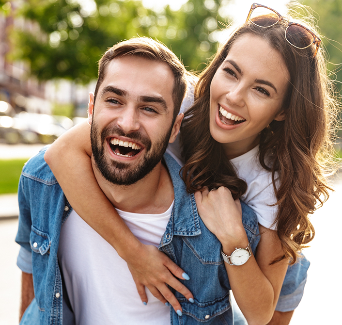 Smiling man and woman outdoors after sedation dentistry in Eugene