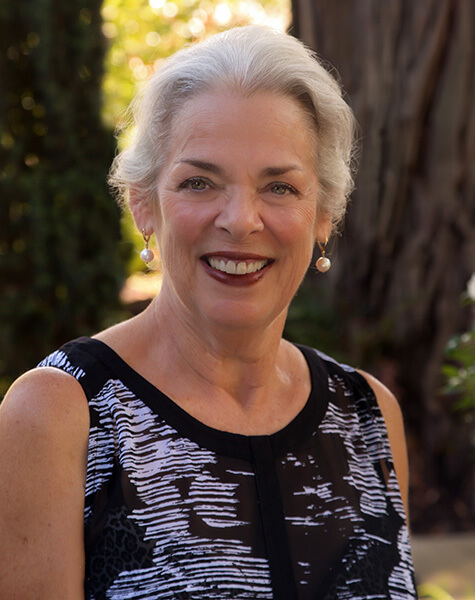 Older woman in sleeveless black top smiling outdoors