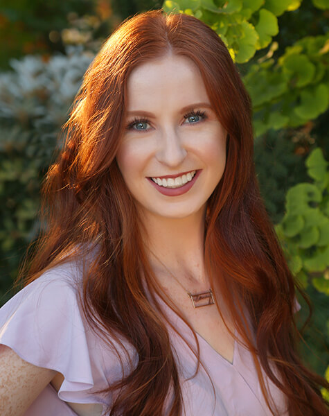 Woman with long red hair smiling outdoors