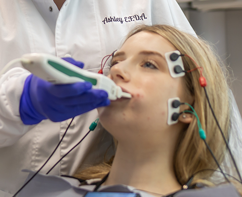 Dental patient hooked up to electrodes while having their mouth scanned